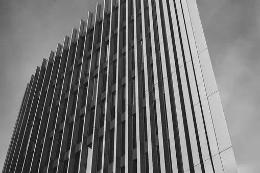 Černobílá fotografie moderní pražské budovy Masaryčka s výraznými vertikálními liniemi.