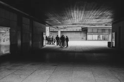 Kontrastní černobílá street fotografie zachycující skupinu lidí na piazzettě Národního divadla.