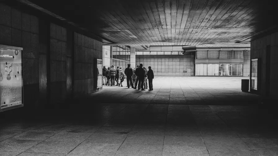 Kontrastní černobílá street fotografie zachycující skupinu lidí na piazzettě Národního divadla.