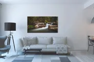 Fotografie horského potoka protékajícího mezi balvany v lese v interiéru moderního obývacího pokoje.